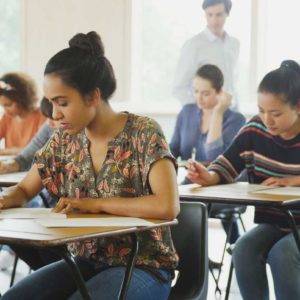 Teilnehmer schreiben konzentriert die A2 Deutsch Prüfung im Klassenzimmer, offizieller Sprachtest für Anfänger mit Grundkenntnissen.