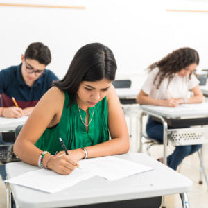 Teilnehmer schreiben konzentriert ihre telc B2 Prüfung im Klassenzimmer, standardisierter Deutschtest für fortgeschrittenes Sprachniveau.
