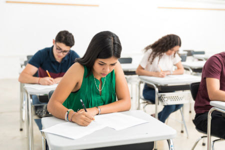 Teilnehmer schreiben konzentriert ihre telc B2 Pr&uuml;fung im Klassenzimmer, standardisierter Deutschtest f&uuml;r fortgeschrittenes Sprachniveau.