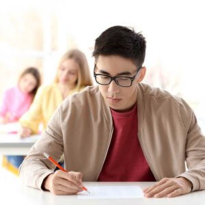 Student schreibt konzentriert die Deutschprüfung C1 Hochschule, offizieller Sprachtest für den Universitätszugang in Deutschland.