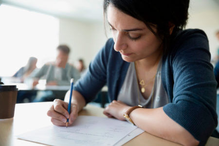 Teilnehmerin schreibt konzentriert eine Pr&uuml;fung zum Deutschzertifikat B2 Beruf, offizieller Sprachtest f&uuml;r den beruflichen Alltag.