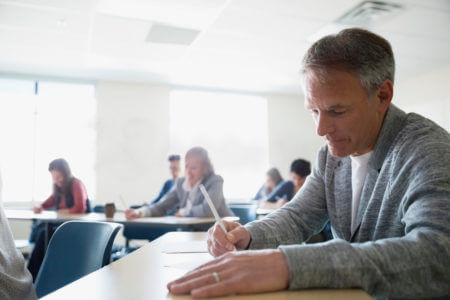 Teilnehmer absolviert konzentriert die C1 telc Deutsch Pr&uuml;fung im Klassenzimmer, offizieller Sprachtest f&uuml;r fortgeschrittenes Niveau.